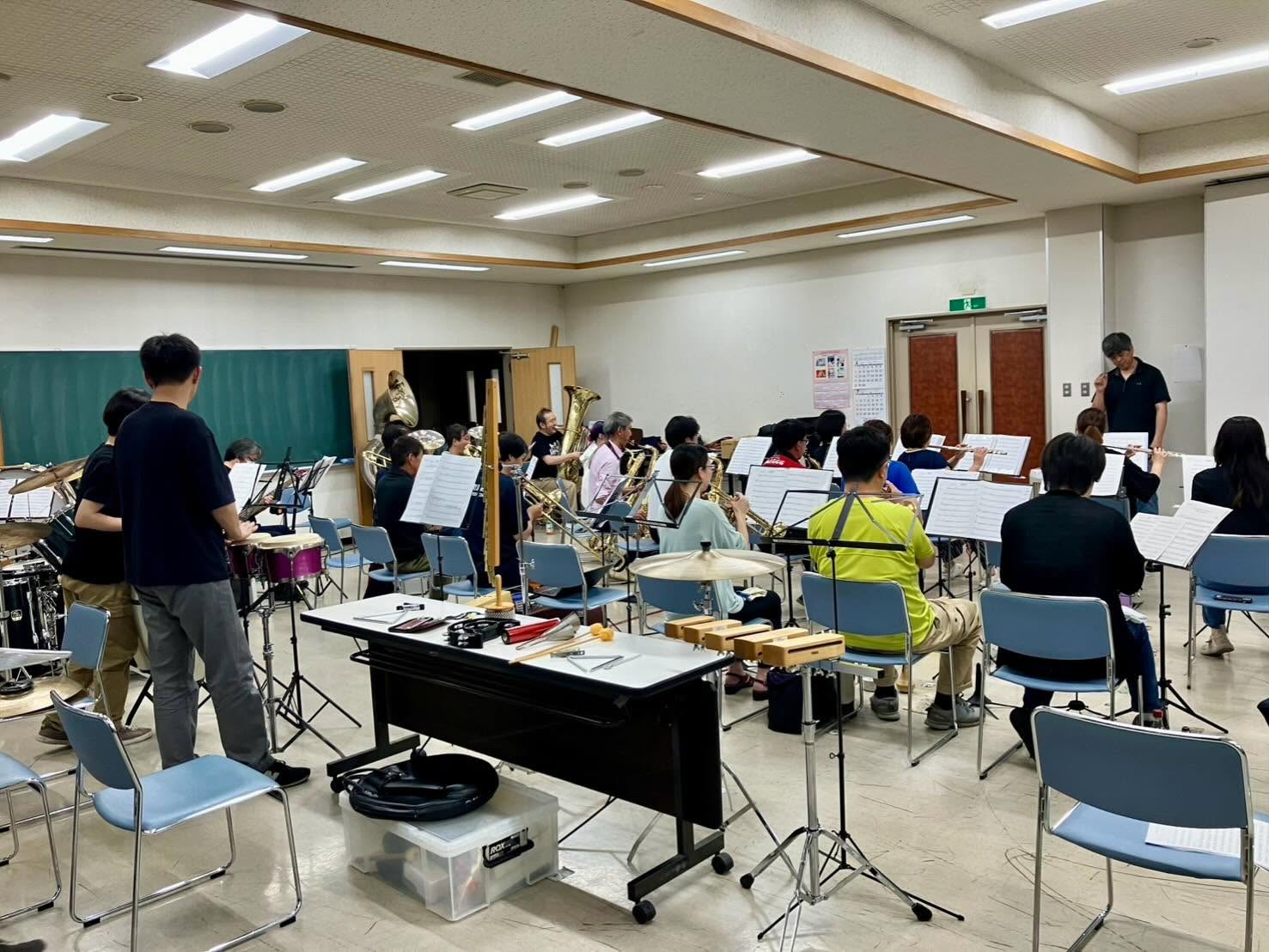 下諏訪町消防団音楽隊の練習場所に有志が集まり、指揮者のもとで合奏する様子